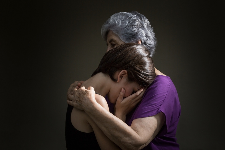 Senior woman hugging granddaughter in grief