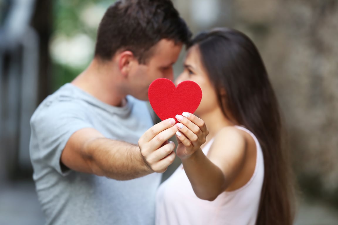 Couple Holding a Red Paper Heart Outdoors